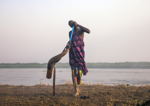 Mundari tribe man blowing in a cow horn, Central Equatoria, Terekeka, South Sudan