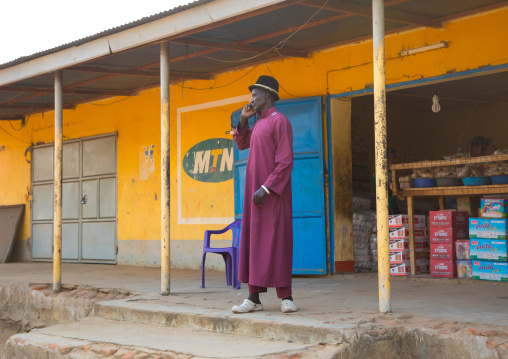 Mundari tribe man calling on mobile phone in front of a shop, Central Equatoria, Terekeka, South Sudan