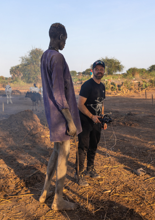Western tourist with a tall Mundari man, Central Equatoria, Terekeka, South Sudan