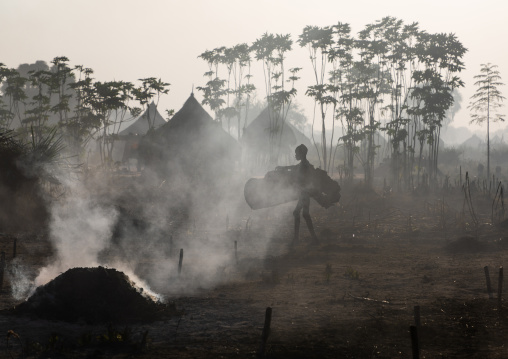 Mundari tribe boy collecting dried cow dungs in a cow skin to make bonfires to repel mosquitoes and flies, Central Equatoria, Terekeka, South Sudan
