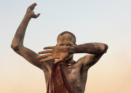 Portrait of a Mundari tribe man mimics the position of horns of his favourite cow, Central Equatoria, Terekeka, South Sudan