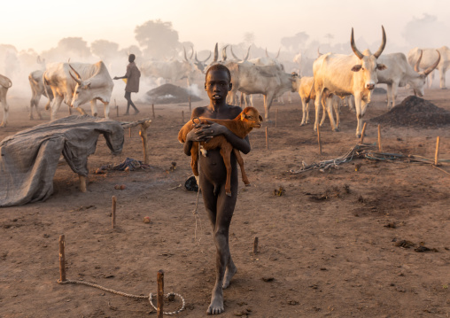 Mundari tribe boy carrying a baby sheep in a camp, Central Equatoria, Terekeka, South Sudan