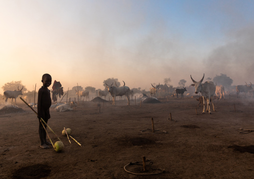 Mundari tribe boy taking care of the bonfires made with dried cow dungs to repel flies and mosquitoes, Central Equatoria, Terekeka, South Sudan