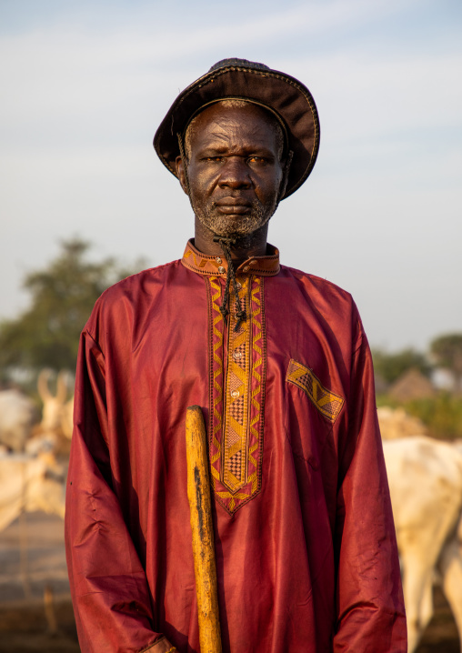 Portrait of a Mundari tribe man in traditional clothing with his cows, Central Equatoria, Terekeka, South Sudan