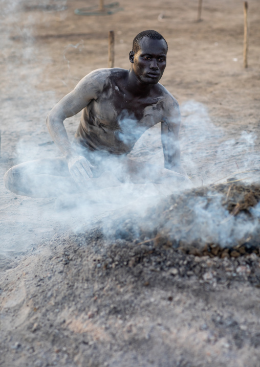 Mundari tribe man taking care of the bonfires made with dried cow dungs to repel mosquitoes, Central Equatoria, Terekeka, South Sudan