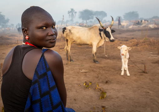 Portrait of a Mundari tribe woman with her long horns cows, Central Equatoria, Terekeka, South Sudan