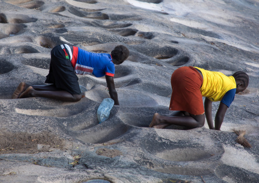 Lotuko tribe woman grinding grains in a hole in the rock, Central Equatoria, Illeu, South Sudan