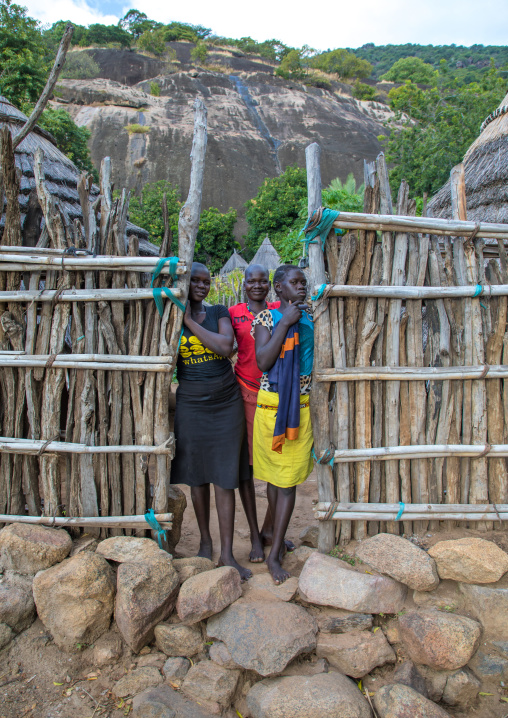 Lotuko tribe girls standing at the wooden gate of a house, Central Equatoria, Illeu, South Sudan