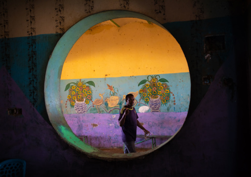 Sudanese man passing inside a circular window in a restaurant, Khartoum State, Khartoum, Sudan