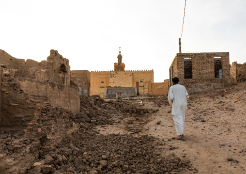 Sudanese man walking thru the abandonned mudbrick houses, Northern State, Al-Khandaq, Sudan