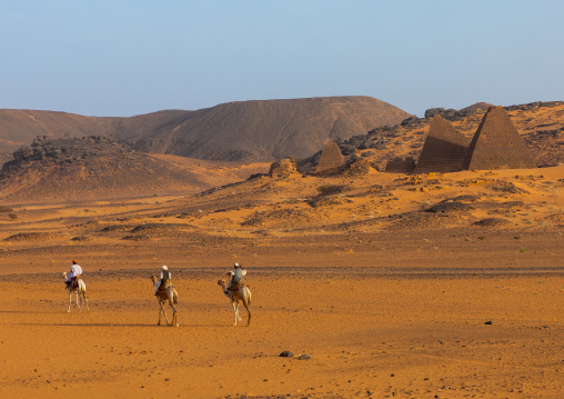 Sudanese men and their camels in front of the pyramids of the kushite rulers at Meroe, Northern State, Meroe, Sudan