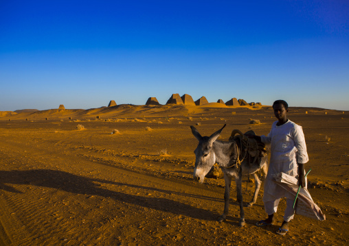 Sudan, Kush, Meroe, kid with his donkey in front of the pyramids and tombs in royal cemetery, meroe