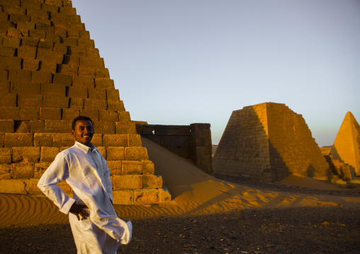 Sudan, Kush, Meroe, young sudanese man in front of the pyramids and tombs in royal cemetery