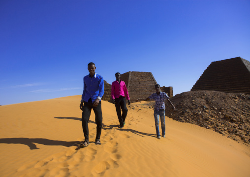 Sudan, Kush, Meroe, young men in front of pyramids and tombs in royal cemetery
