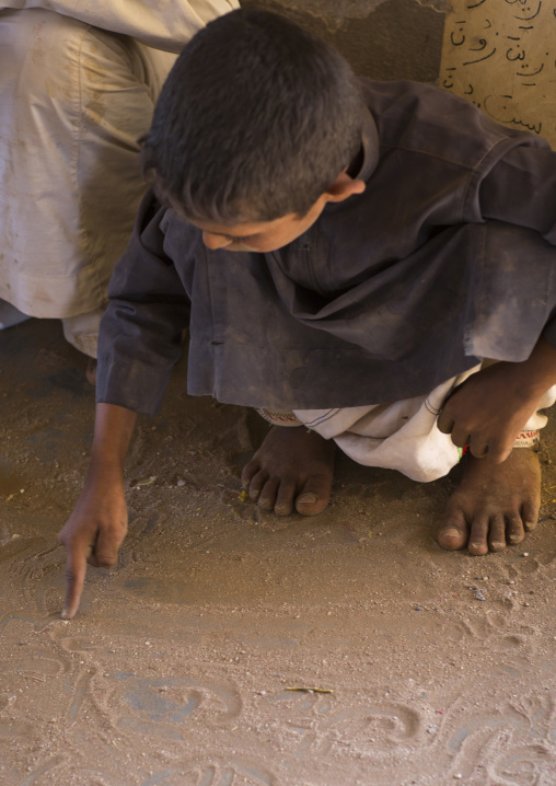 Sudan, Kassala State, Kassala, rashaida tribe kid writing on the sand in a coranic school