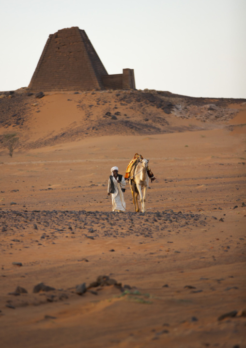 Sudan, Kush, Meroe, man and his camel in front of the pyramids and tombs in royal cemetery