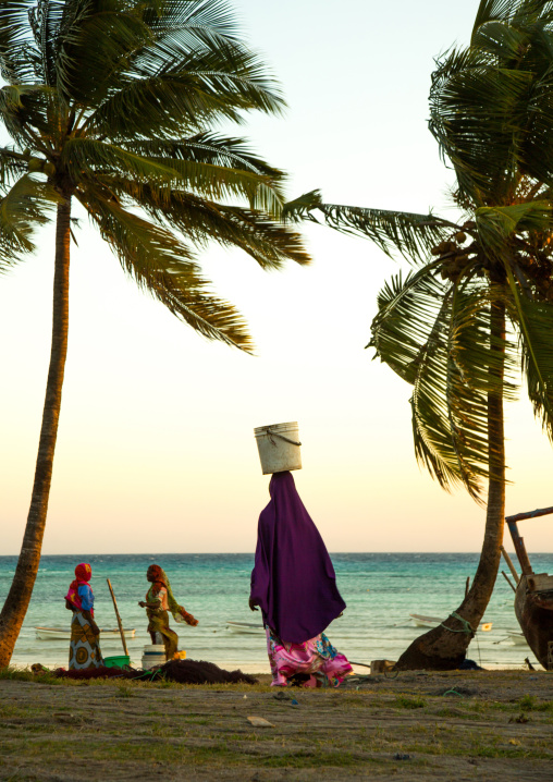Tanzania, Zanzibar, Kizimkazi, women carrying fishes in a bucket on their heads