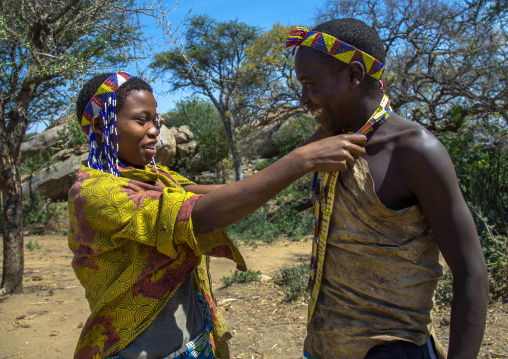 Tanzania, Serengeti Plateau, Lake Eyasi, hadzabe tribe woman offeringa necklace to a man to show him her love