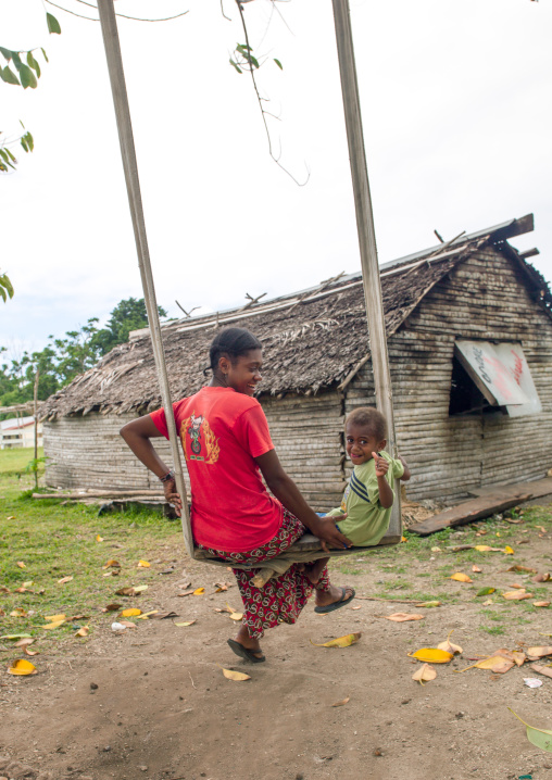 A mother and her son on a swing in front of their house, Shefa Province, Efate island, Vanuatu