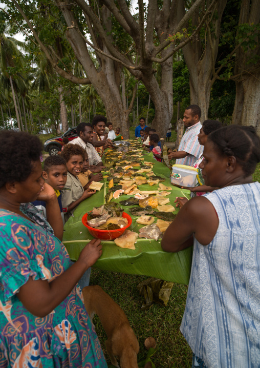 Family eating together some yam cooked in traditional oven on a sunday lunch in a park, Malampa Province, Malekula Island, Vanuatu