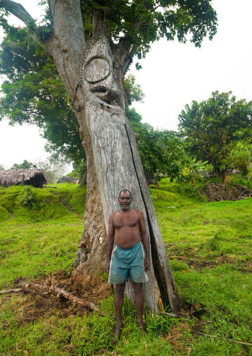 Ni-Vanuatu man standing in front of a giant slit gong drum, Ambrym island, Olal, Vanuatu