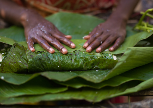 Woman cooking a bougna in a green banana leaf, Tanna island, Epai, Vanuatu