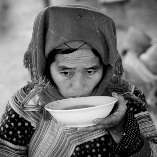 Flower hmong woman drinking a bowl of soup, Sapa market, Vietnam
