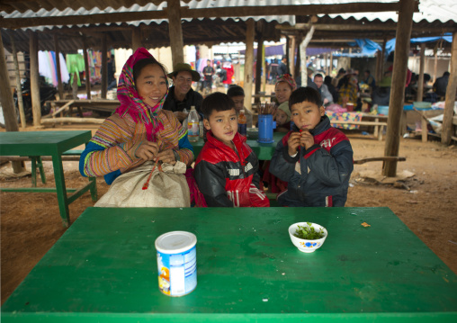 Flower hmong woman and her sons sitting on a table for lunch, Sapa market, Vietnam