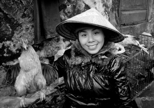 Woman with a sedge hat showing a chicken she sells, Sapa, Vietnam
