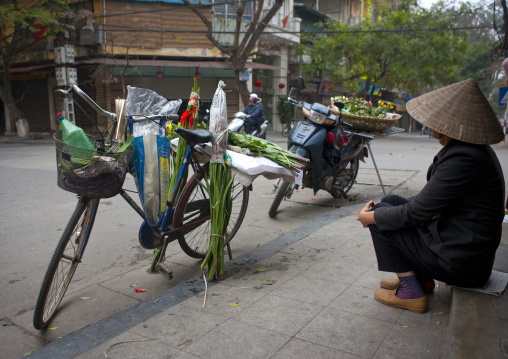 Woman sitting next to his bike in the street, Hanoi, Vietnam