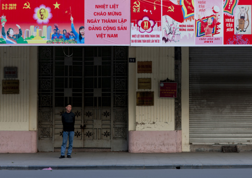 Man under propaganda panels of the communist party, Hanoi, Vietnam