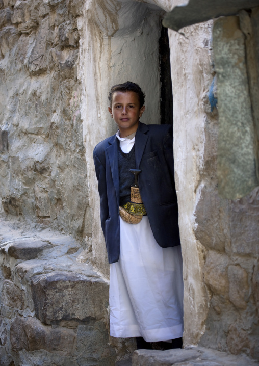 Young Boy In Adult Clothes And Wearing Jambiya In Front Of A Door, Thula, Yemen
