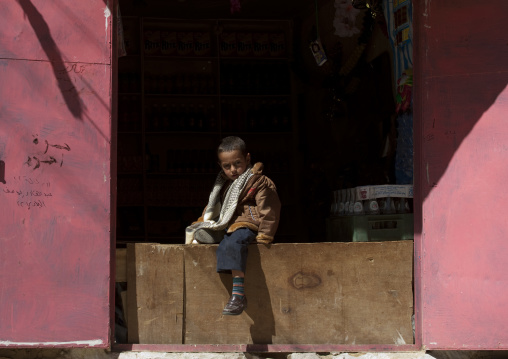 Young Boy Sitting On A Plank Barring The Entrance Of A Shop, Thula, Yemen