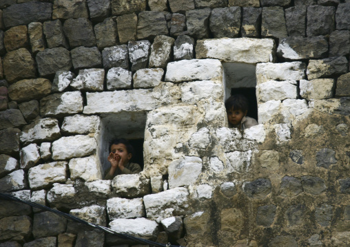 Two Kids Looking Outside From The Small Windows Of A House, Al Hajjara, Yemen