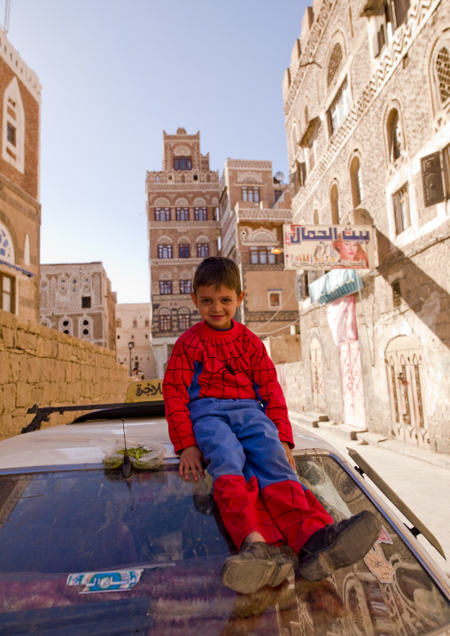 Smiling Kid Wearing A Spiderman Suit And Adult Shoes, Sitting On The Top Of A Car, Sanaa, Yemen