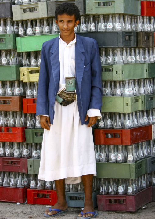 Yemeni man with jambiya in front of empty bottles, Taiz Governorate, Mokha, Yemen