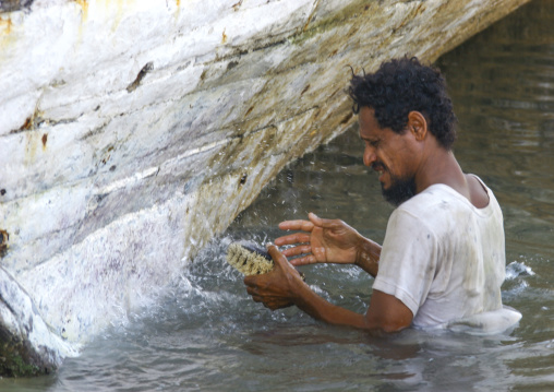 Yemeni man cleaning a boat in the water, Al Hudaydah Governorate, Hodeidah, Yemen