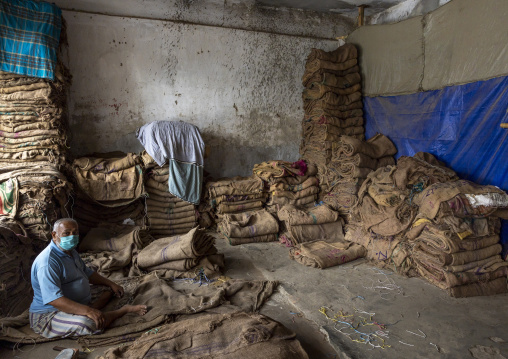Bangladeshi man packing burlap sacks in Kawran bazar, Dhaka Division, Dhaka, Bangladesh