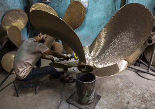 Dockyard worker polishing a propeller, Dhaka Division, Keraniganj, Bangladesh