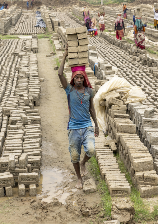 A bangladeshi man carries bricks on his head at a brick factory, Sylhet Division, Bahubal, Bangladesh