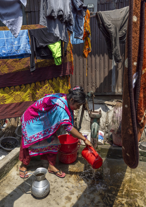 Bangladeshi woman pumping water at a pump in Sundarbans, Khulna Division, Narail Sadar, Bangladesh