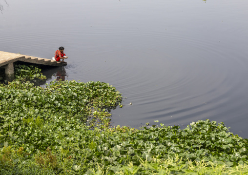 Bangladeshi woman washing clothes in a river, Dhaka Division, Rupganj, Bangladesh