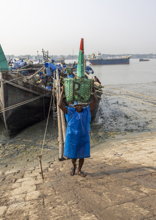 A bangladeshi porter carries a load from a trawler at the morning fish market, Chittagong Division, Chittagong, Bangladesh