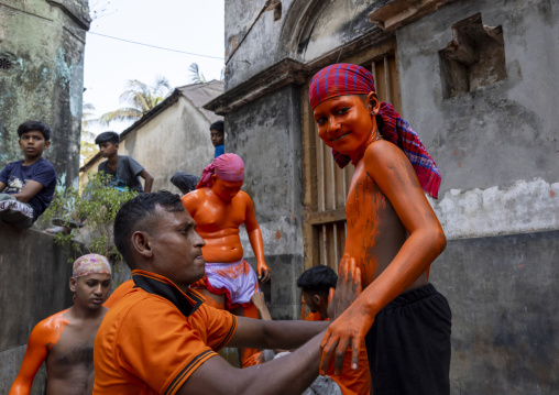 Make up of a young Hindu devotee covered with orange color at Lal Kach festival, Dhaka Division, Munshiganj, Bangladesh