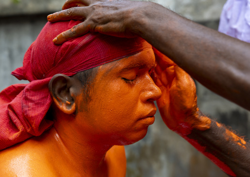Make up of a Hindu devotee covered with orange color at Lal Kach festival, Dhaka Division, Munshiganj, Bangladesh