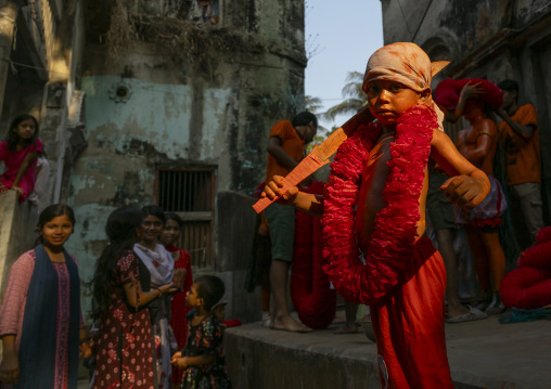 Young hindu devotee in orange color playing with sword at Lal Kach festival, Dhaka Division, Munshiganj, Bangladesh