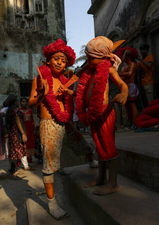 Young hindu devotees in orange color playing with swords at Lal Kach festival, Dhaka Division, Munshiganj, Bangladesh