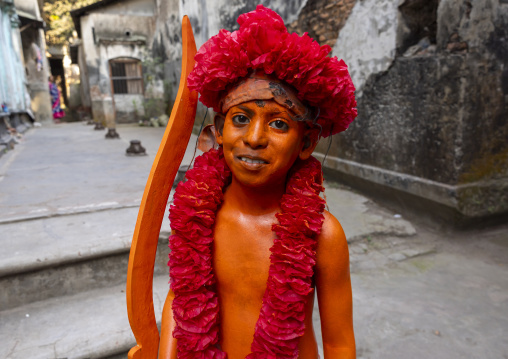 Young hindu devotee in orange color playing with sword at Lal Kach festival, Dhaka Division, Munshiganj, Bangladesh