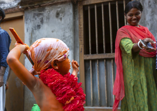 Young hindu devotee in orange color playing with sword at Lal Kach festival, Dhaka Division, Munshiganj, Bangladesh