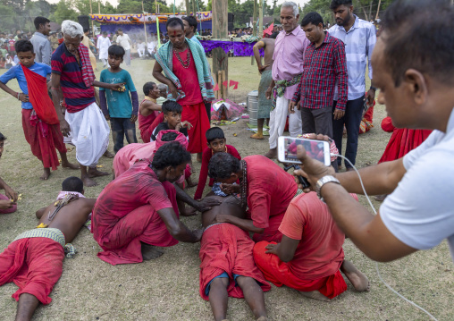 Men putting a hook in the back of a man for a body suspension in Charak Puja, Sylhet Division, Kamalganj, Bangladesh